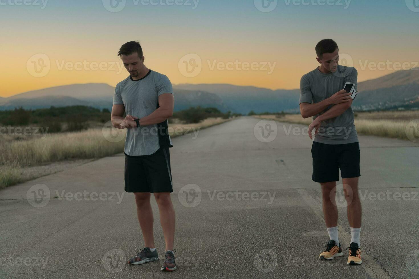 Sport couple looking at a smartwatch while standing on the country road. Resting after jogging and running exercise and checking heart rate and pulse. photo