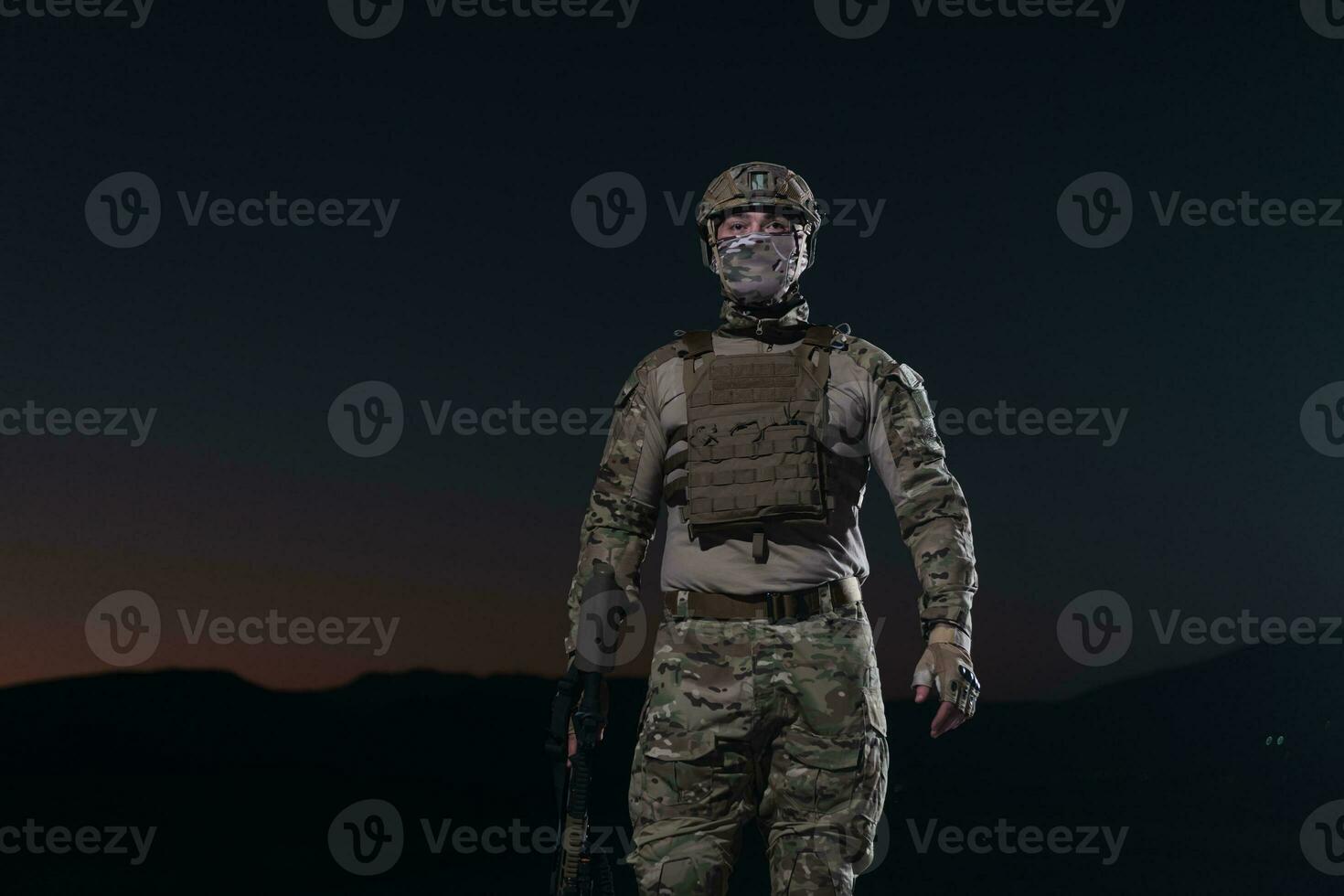 Ejército soldado en combate uniformes con un asalto rifle, plato portador y combate casco yendo en un peligroso misión en un lluvioso noche. foto