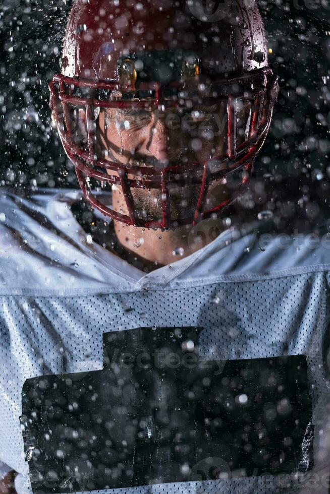 American Football Field Lonely Athlete Warrior Standing on a Field Holds his Helmet and Ready to Play. Player Preparing to Run, Attack and Score Touchdown. Rainy Night with Dramatic Fog, Blue Light photo