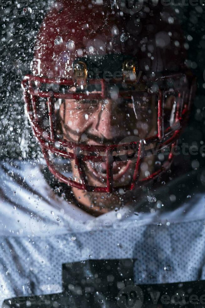 American Football Field Lonely Athlete Warrior Standing on a Field Holds his Helmet and Ready to Play. Player Preparing to Run, Attack and Score Touchdown. Rainy Night with Dramatic Fog, Blue Light photo
