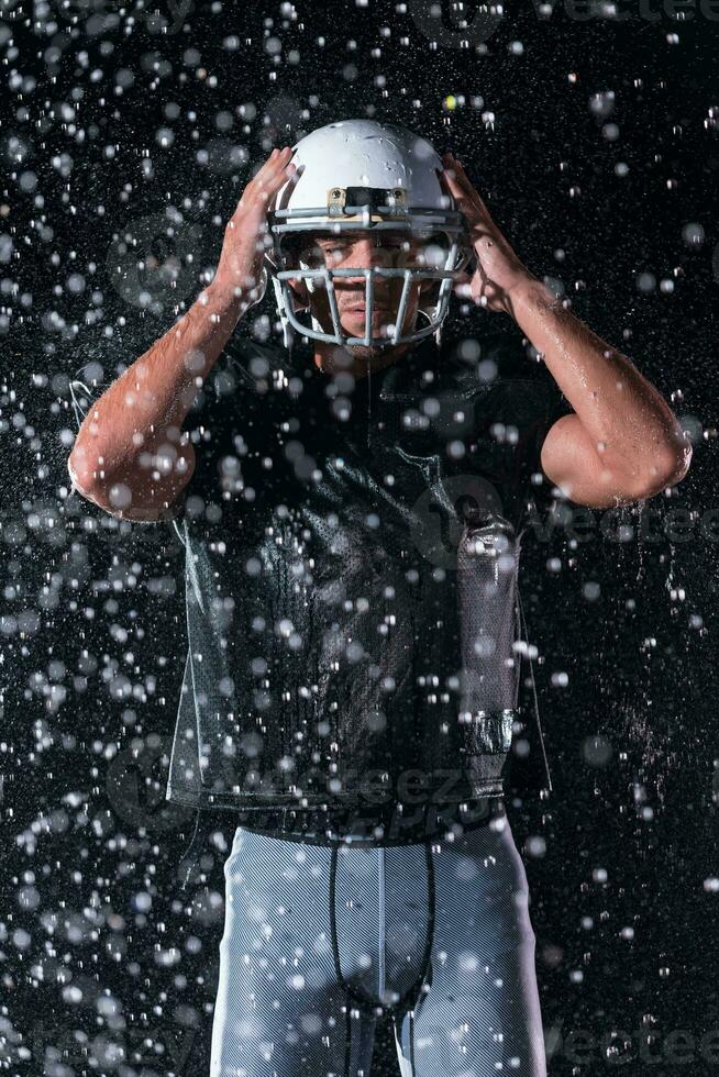 American Football Field Lonely Athlete Warrior Standing on a Field Holds his Helmet and Ready to Play. Player Preparing to Run, Attack and Score Touchdown. Rainy Night with Dramatic Fog, Blue Light photo
