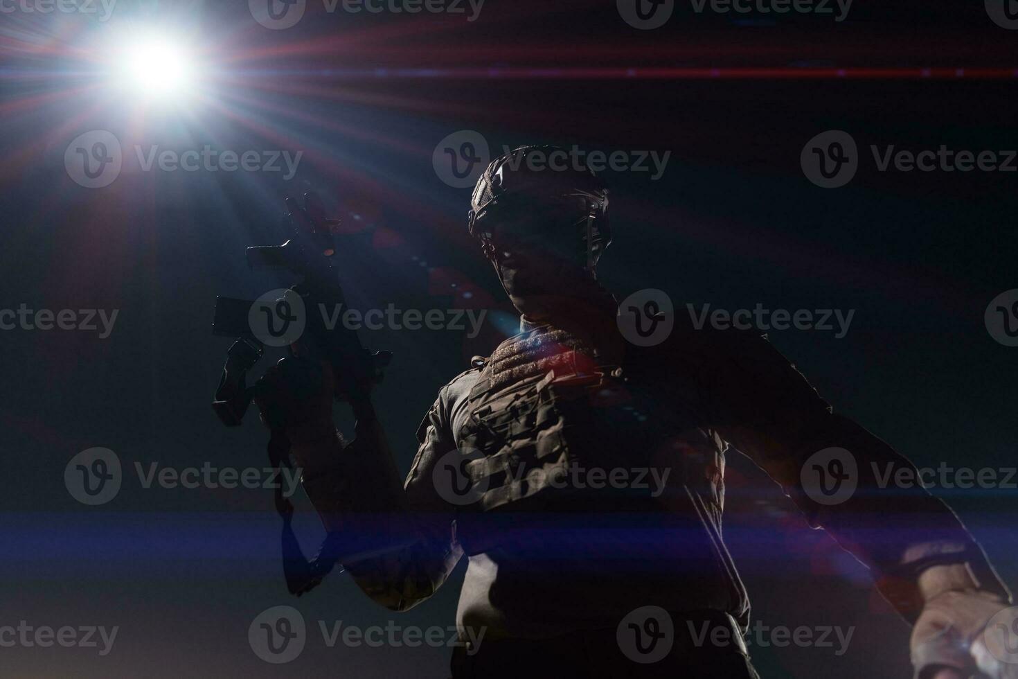 Army soldier in Combat Uniforms with an assault rifle, plate carrier and combat helmet going on a dangerous mission on a rainy night. photo