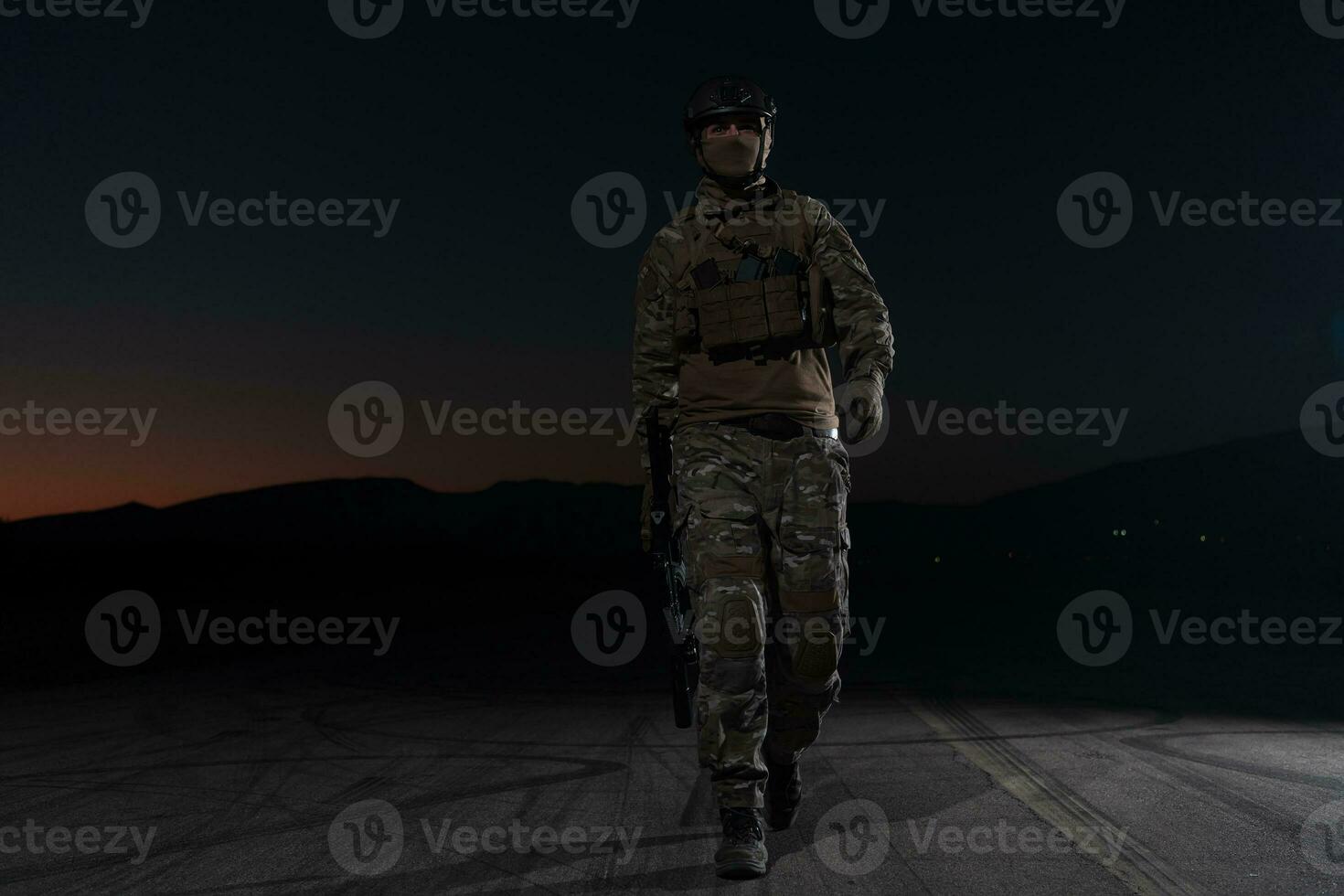 Ejército soldado en combate uniformes con un asalto rifle, plato portador y combate casco yendo en un peligroso misión en un lluvioso noche. foto