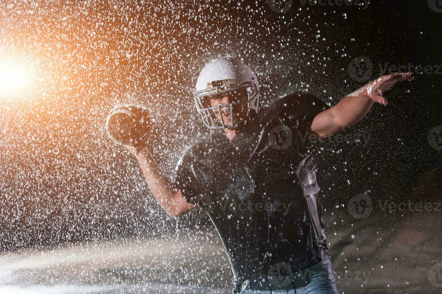 American Football Field Lonely Athlete Warrior Standing on a Field Holds his Helmet and Ready to Play. Player Preparing to Run, Attack and Score Touchdown. Rainy Night with Dramatic Fog, Blue Light photo