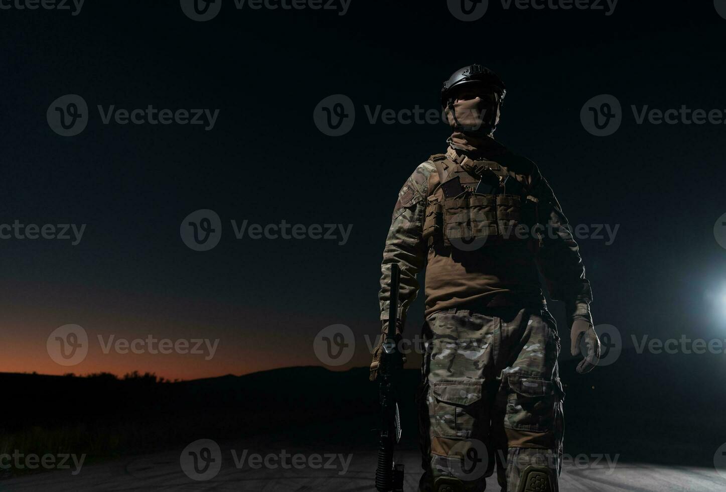 Ejército soldado en combate uniformes con un asalto rifle, plato portador y combate casco yendo en un peligroso misión en un lluvioso noche. foto