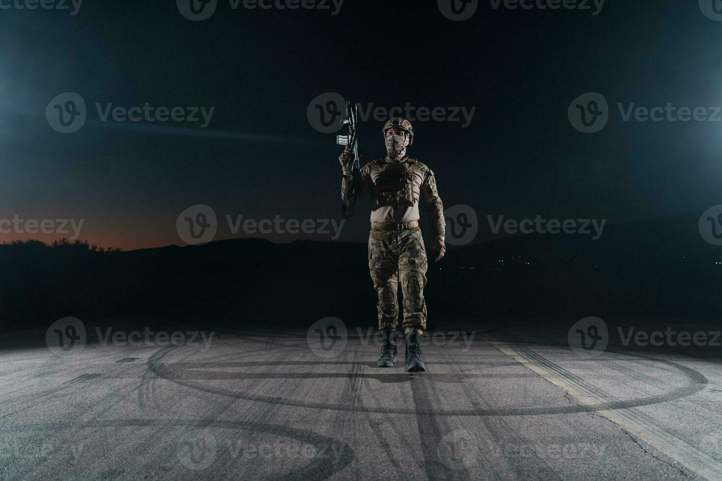 Army soldier in Combat Uniforms with an assault rifle, plate carrier and combat helmet going on a dangerous mission on a rainy night. photo