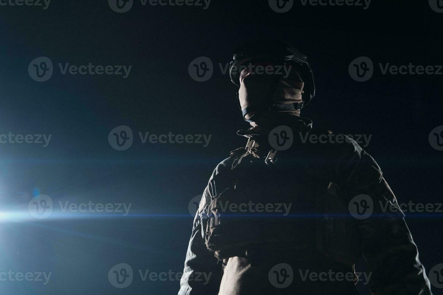 Army soldier in Combat Uniforms with an assault rifle, plate carrier and combat helmet going on a dangerous mission on a rainy night. photo