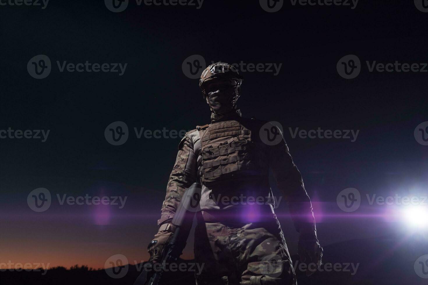 Ejército soldado en combate uniformes con un asalto rifle, plato portador y combate casco yendo en un peligroso misión en un lluvioso noche. foto