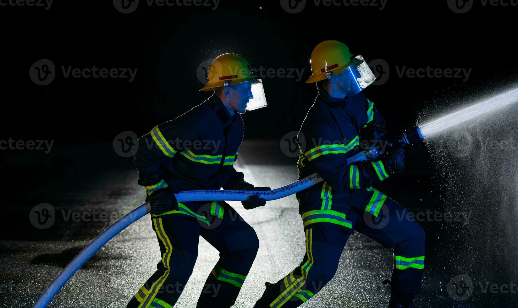 Firefighters use a water hose to eliminate a fire hazard. Team of firemen in the dangerous rescue mission. photo