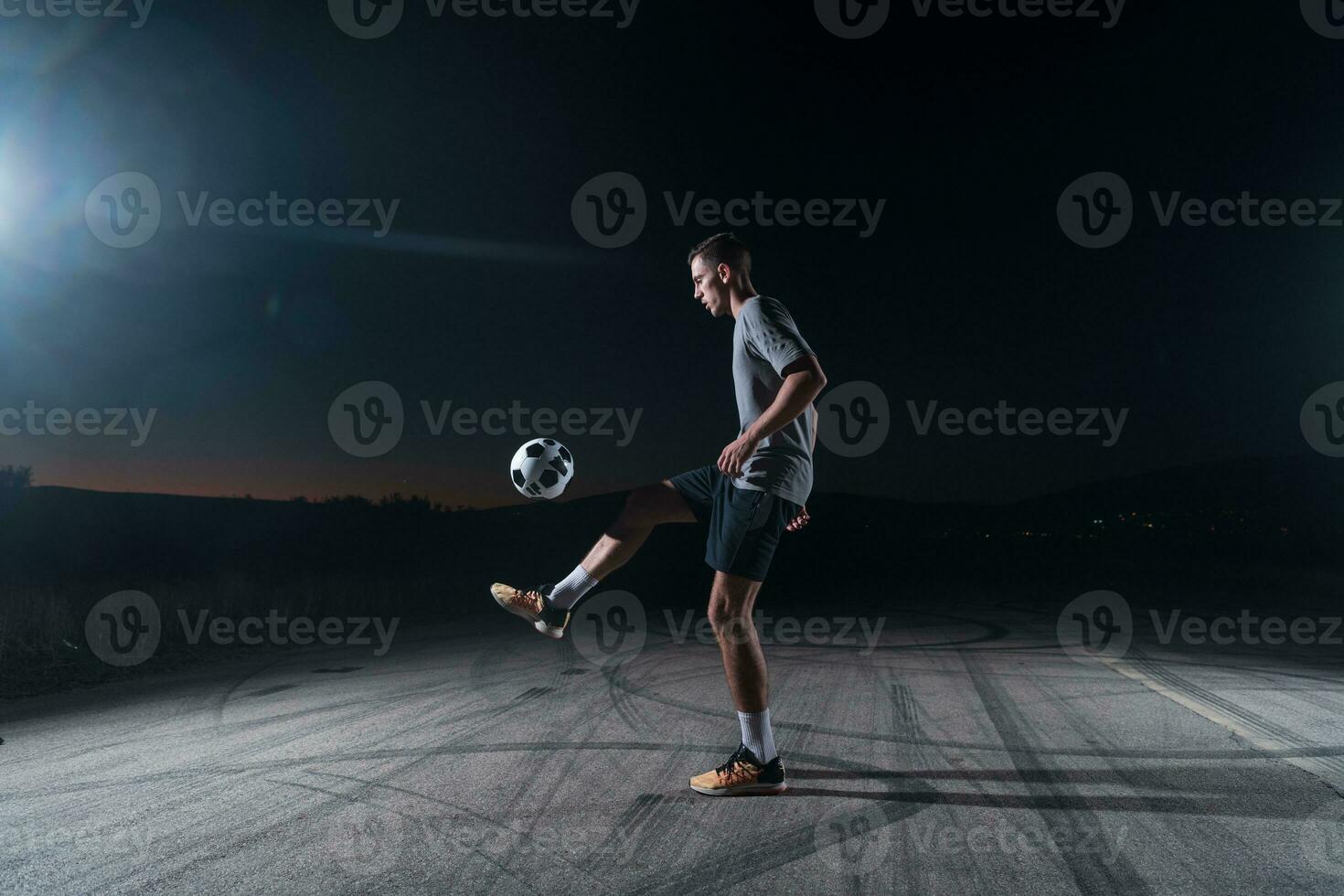 portrait of a young handsome soccer player man on a street playing with a football ball. photo