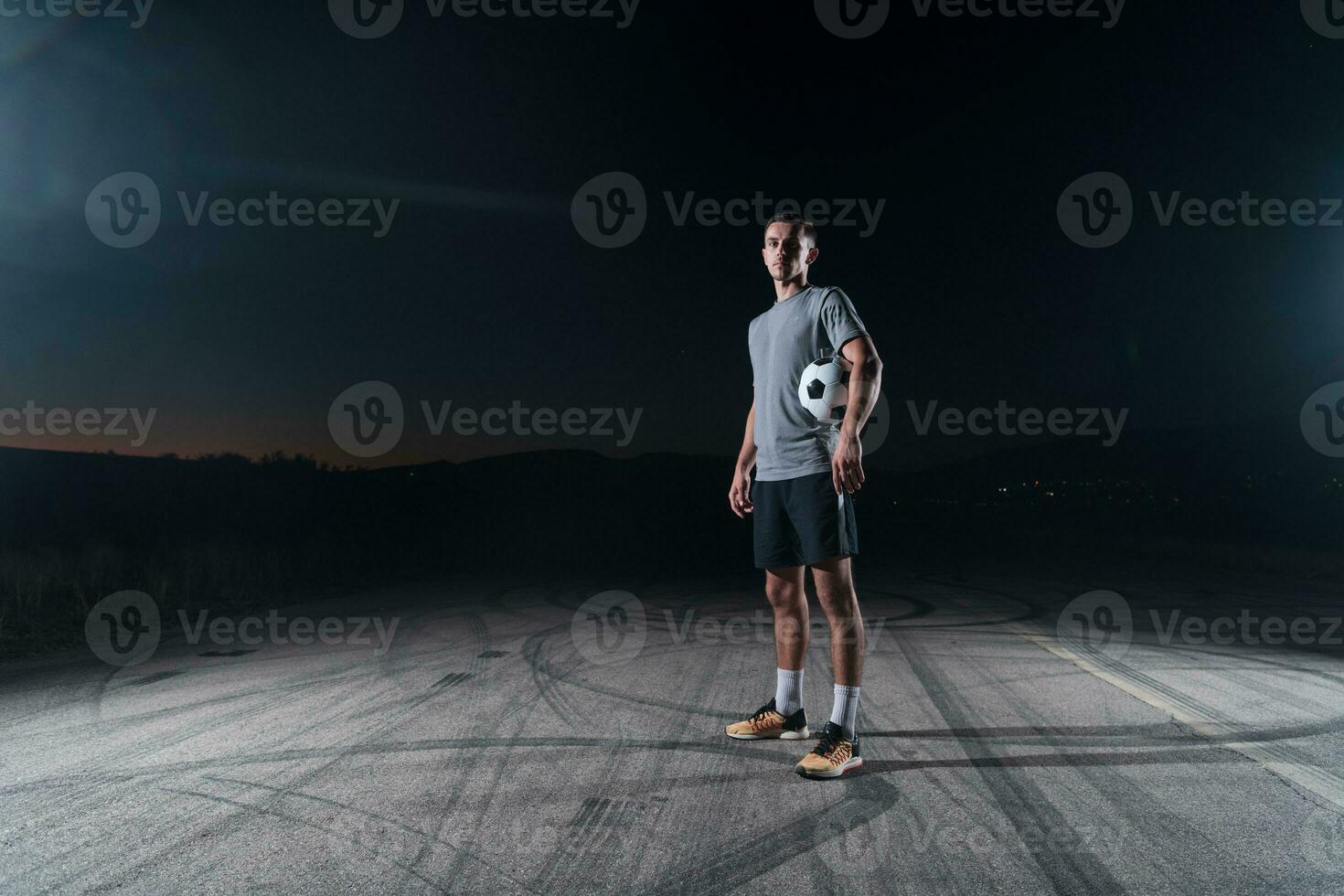 portrait of a young handsome soccer player man on a street playing with a football ball. photo