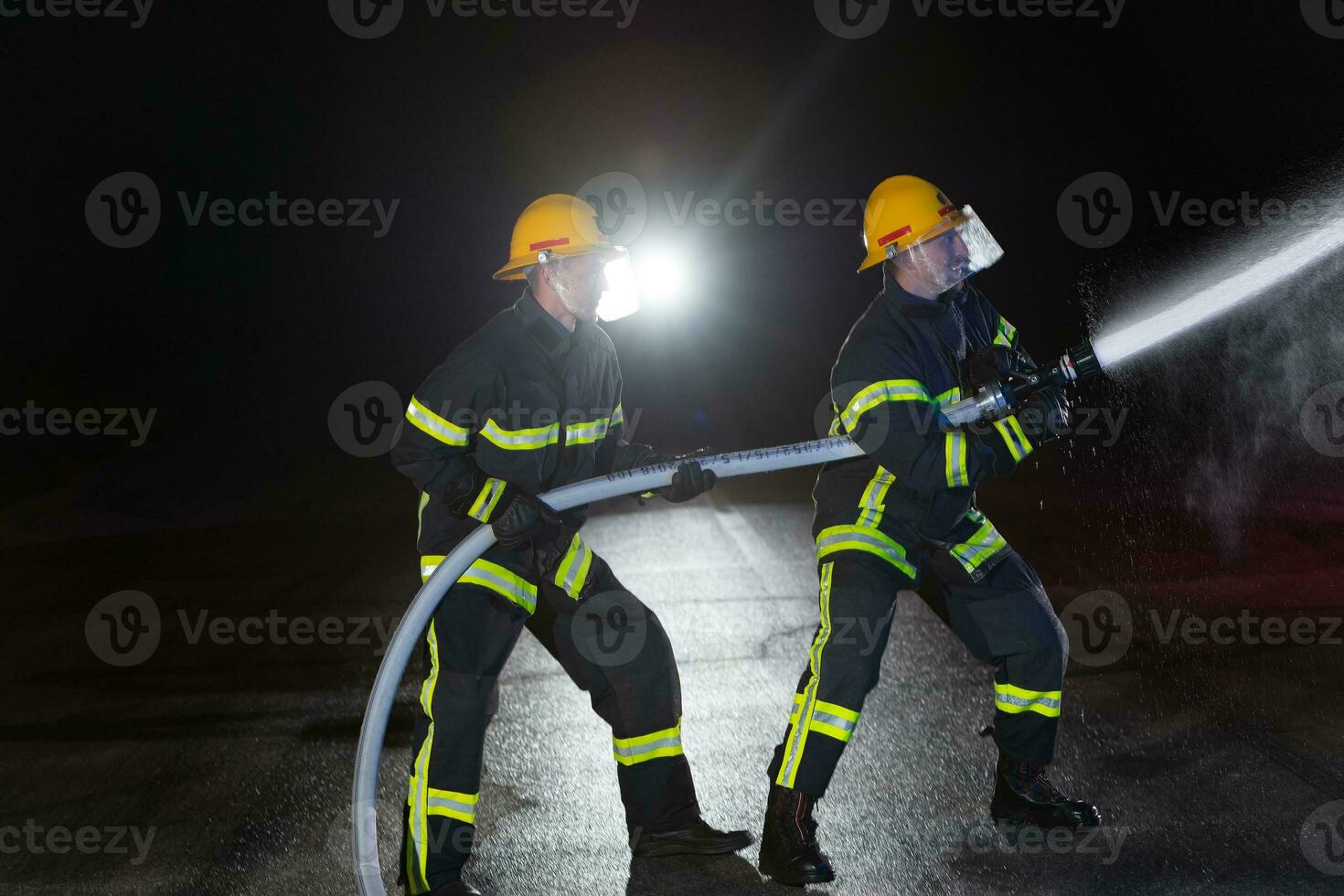 Firefighters use a water hose to eliminate a fire hazard. Team of firemen in the dangerous rescue mission. photo