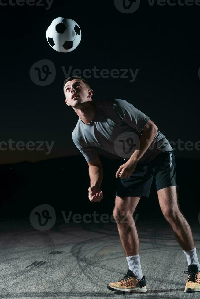 portrait of a young handsome soccer player man on a street playing with a football ball. photo