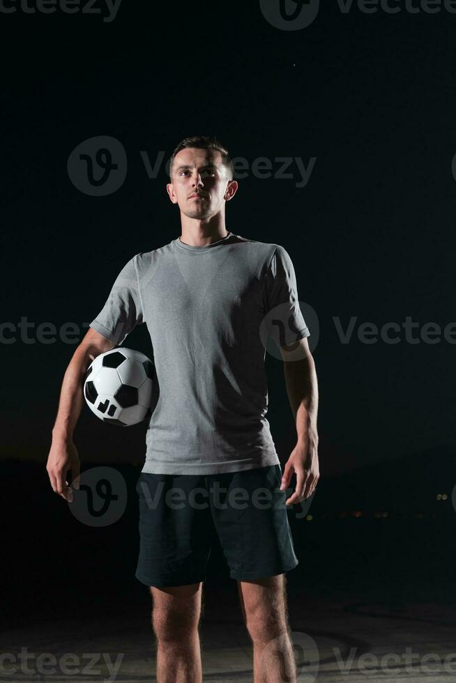 portrait of a young handsome soccer player man on a street playing with a football ball. photo