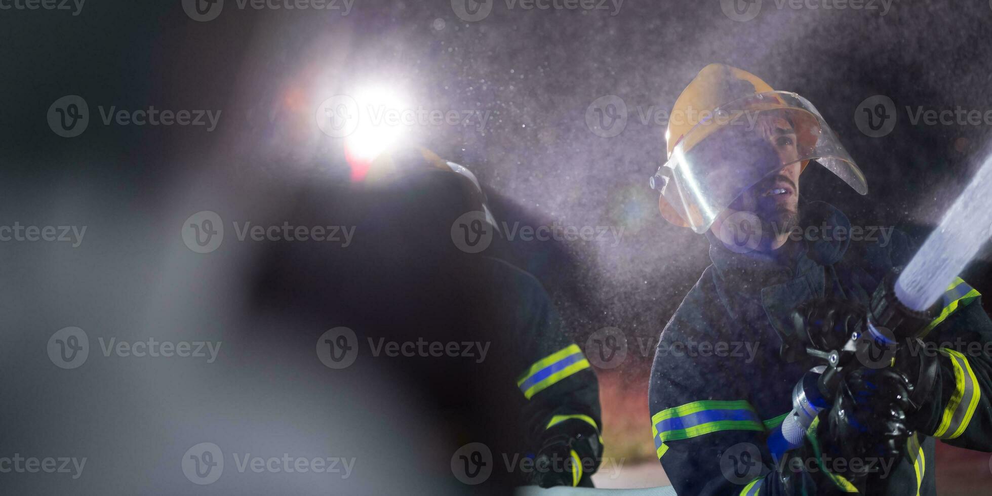 bomberos utilizando un agua manguera a eliminar un fuego peligro. equipo de hembra y masculino bomberos en peligroso rescate misión. foto