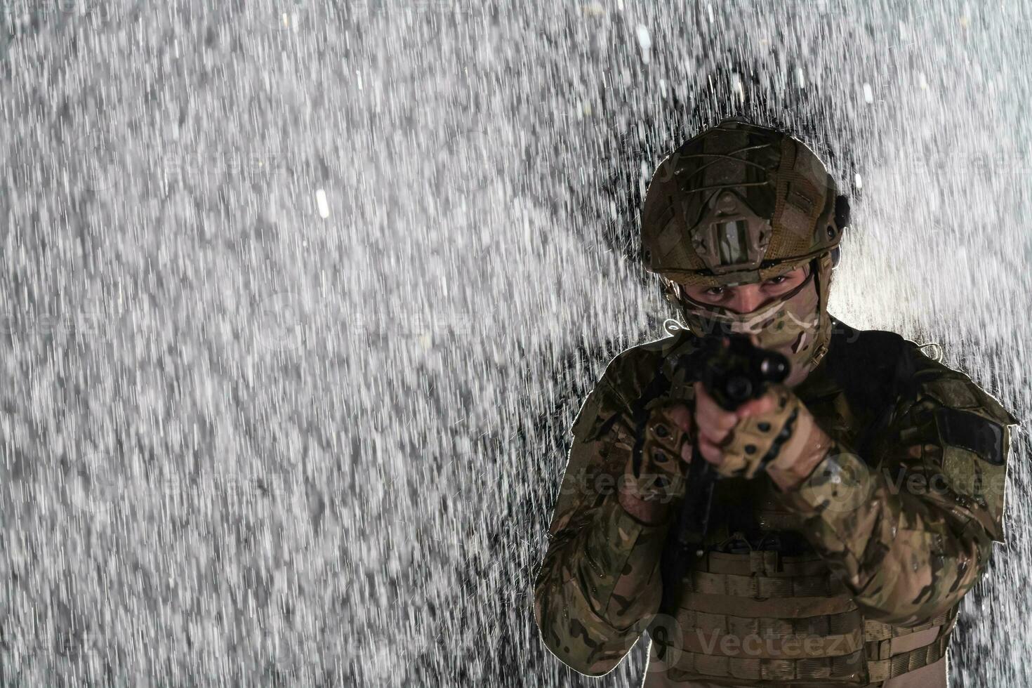 Army soldier in Combat Uniforms with an assault rifle, plate carrier and combat helmet going on a dangerous mission on a rainy night. photo