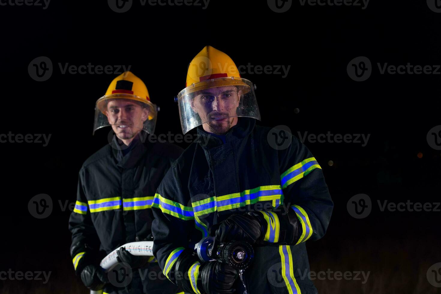 Firefighters use a water hose to eliminate a fire hazard. Team of firemen in the dangerous rescue mission. photo