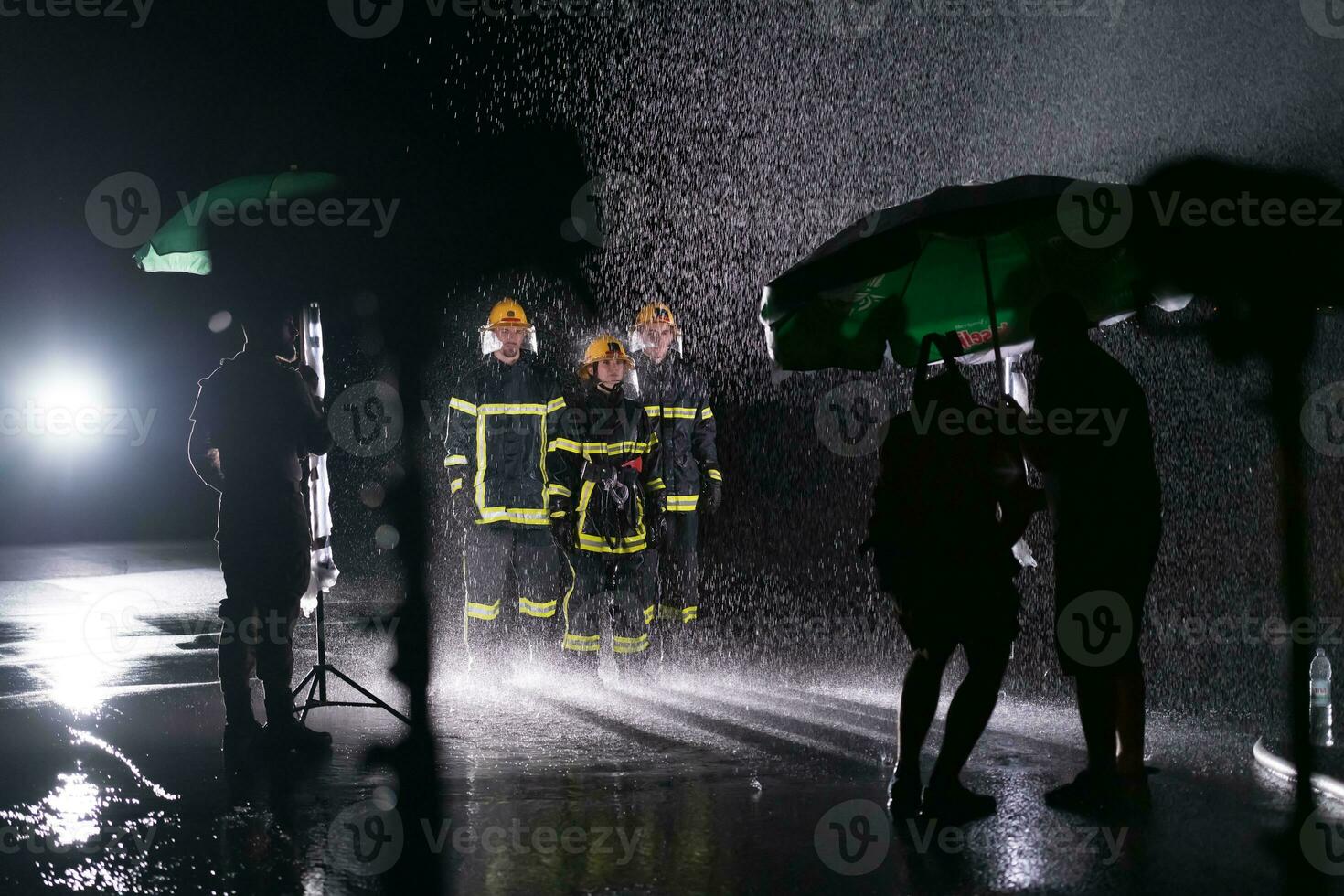 Behind the scene of Firefighters photo and cinema set with rain use a water hose to eliminate a fire hazard.