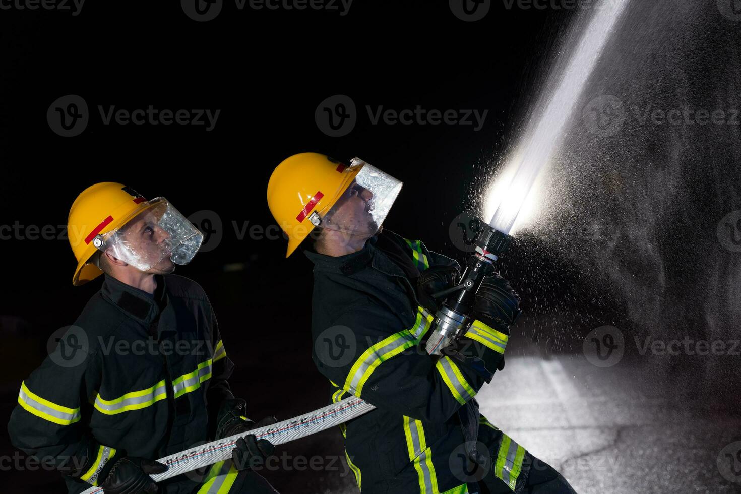 Firefighters use a water hose to eliminate a fire hazard. Team of firemen in the dangerous rescue mission. photo