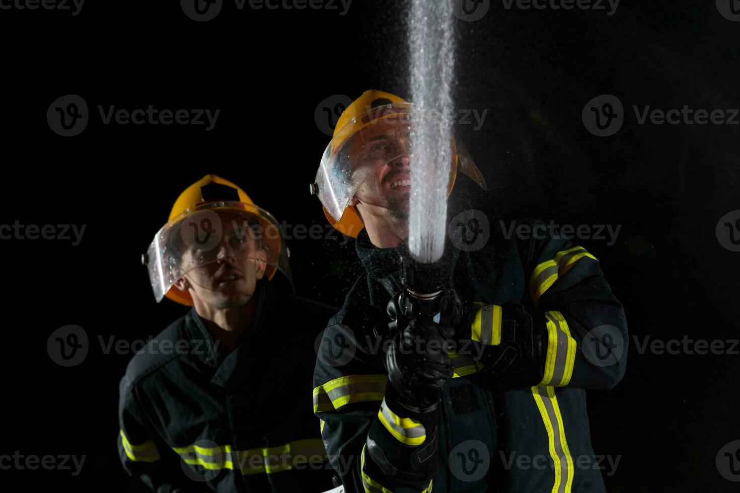 Firefighters use a water hose to eliminate a fire hazard. Team of firemen in the dangerous rescue mission. photo