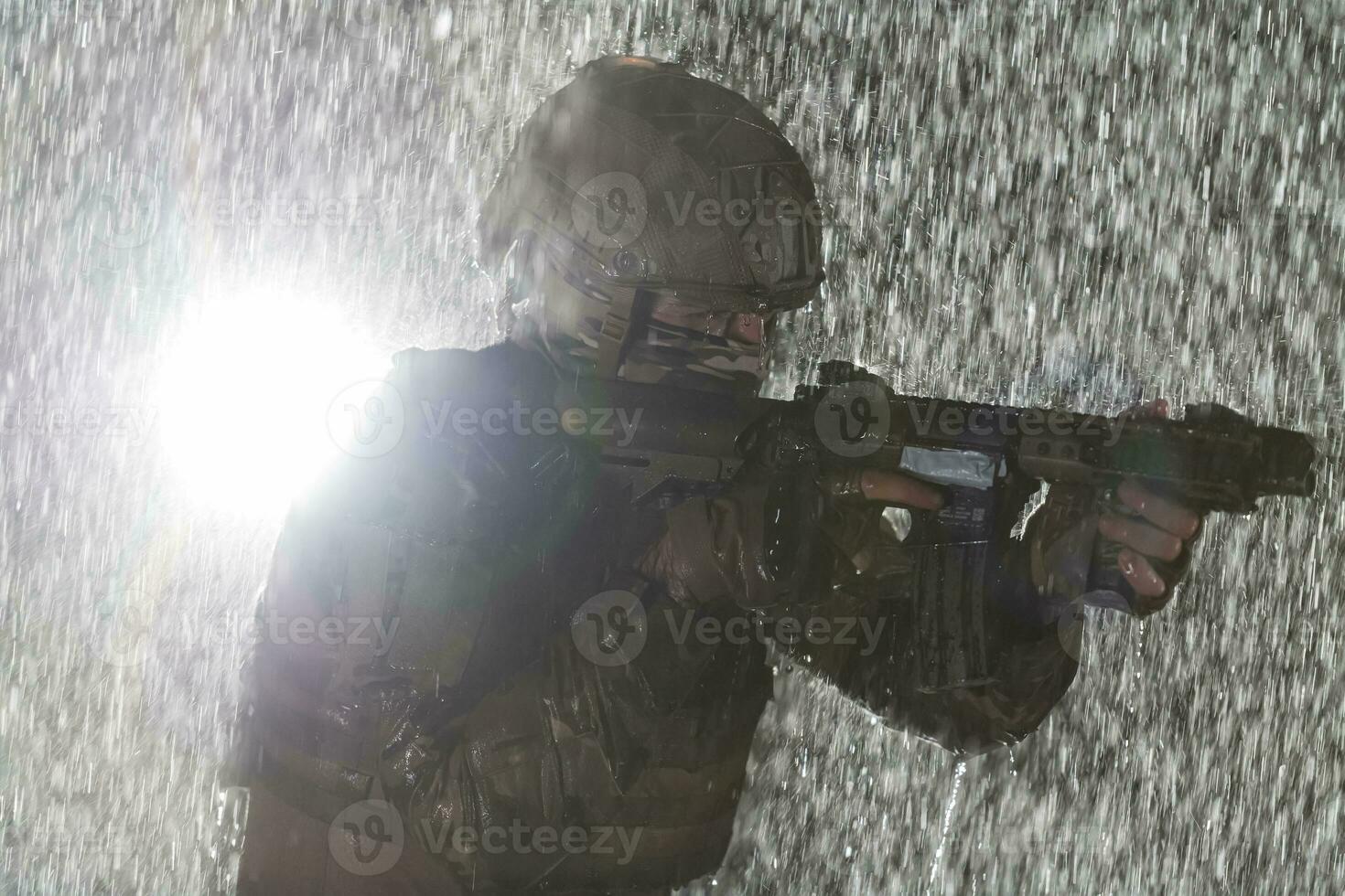 Ejército soldado en combate uniformes con un asalto rifle, plato portador y combate casco yendo en un peligroso misión en un lluvioso noche. foto