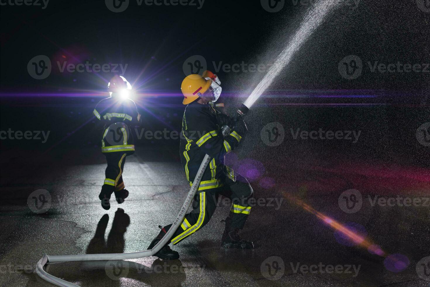 Firefighters use a water hose to eliminate a fire hazard. Team of firemen in the dangerous rescue mission. photo