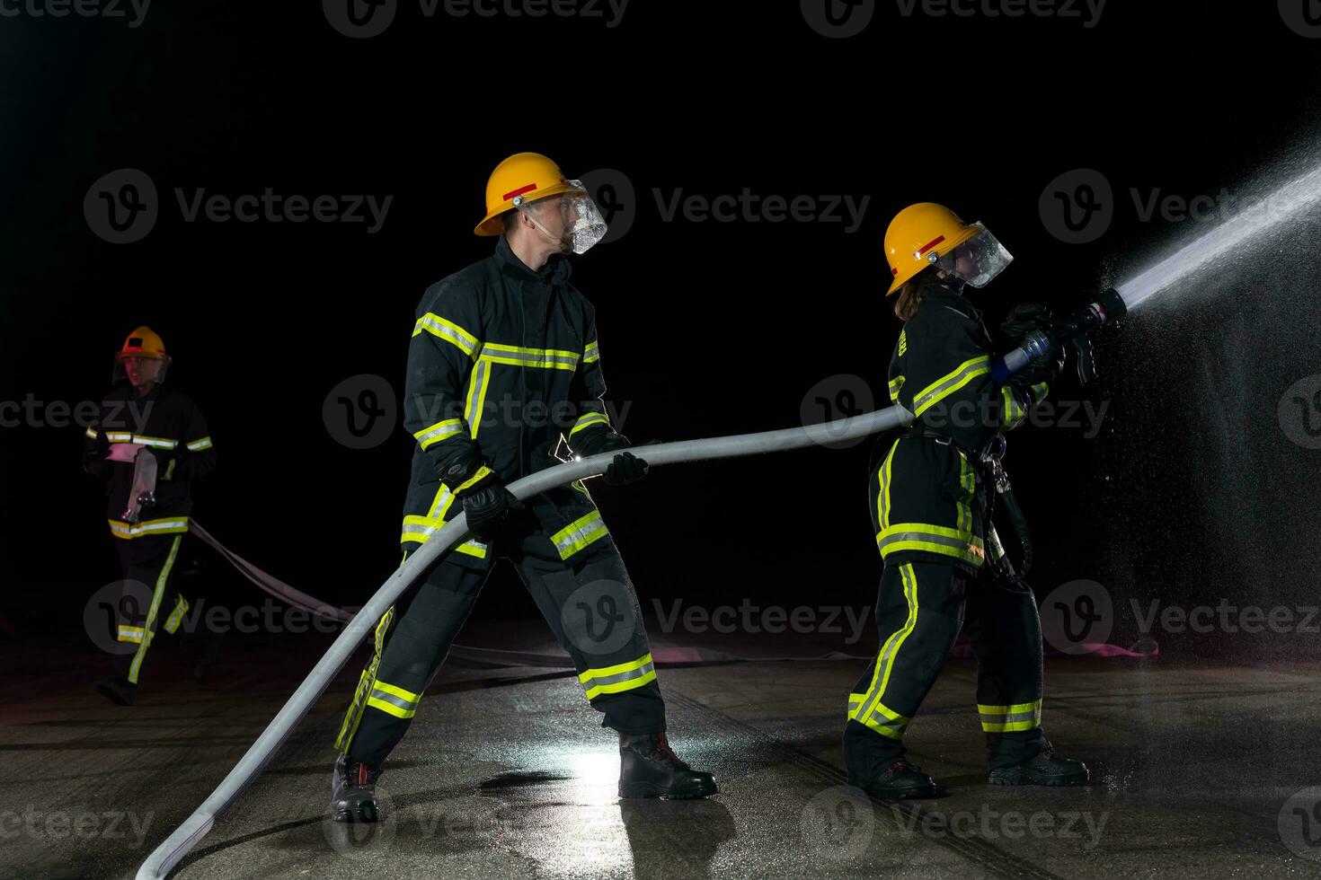 Firefighters using a water hose to eliminate a fire hazard. Team of female and male firemen in dangerous rescue mission. photo