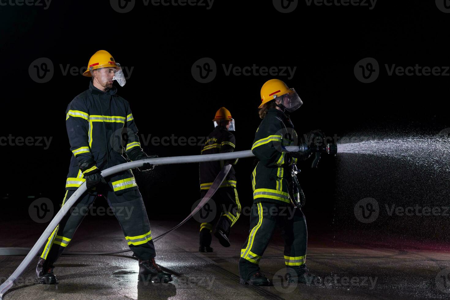 bomberos utilizando un agua manguera a eliminar un fuego peligro. equipo de hembra y masculino bomberos en peligroso rescate misión. foto