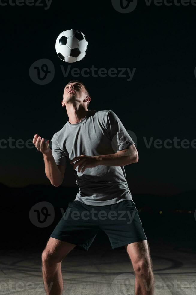 portrait of a young handsome soccer player man on a street playing with a football ball. photo