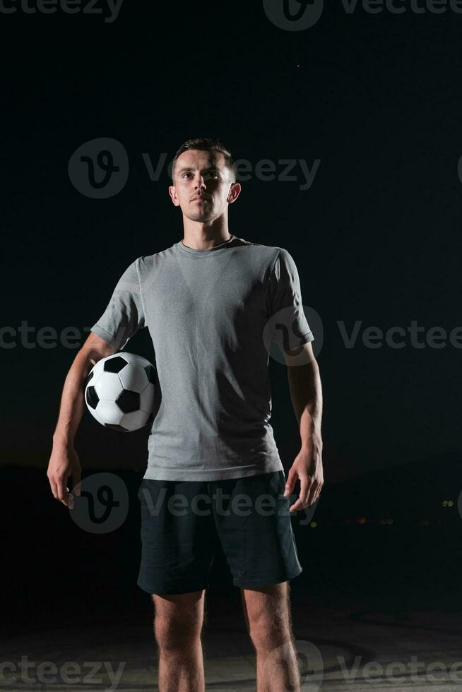 portrait of a young handsome soccer player man on a street playing with a football ball. photo