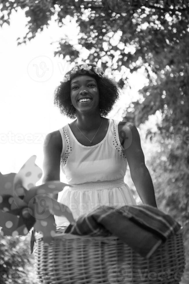 pretty young african american woman riding a bike in forest photo
