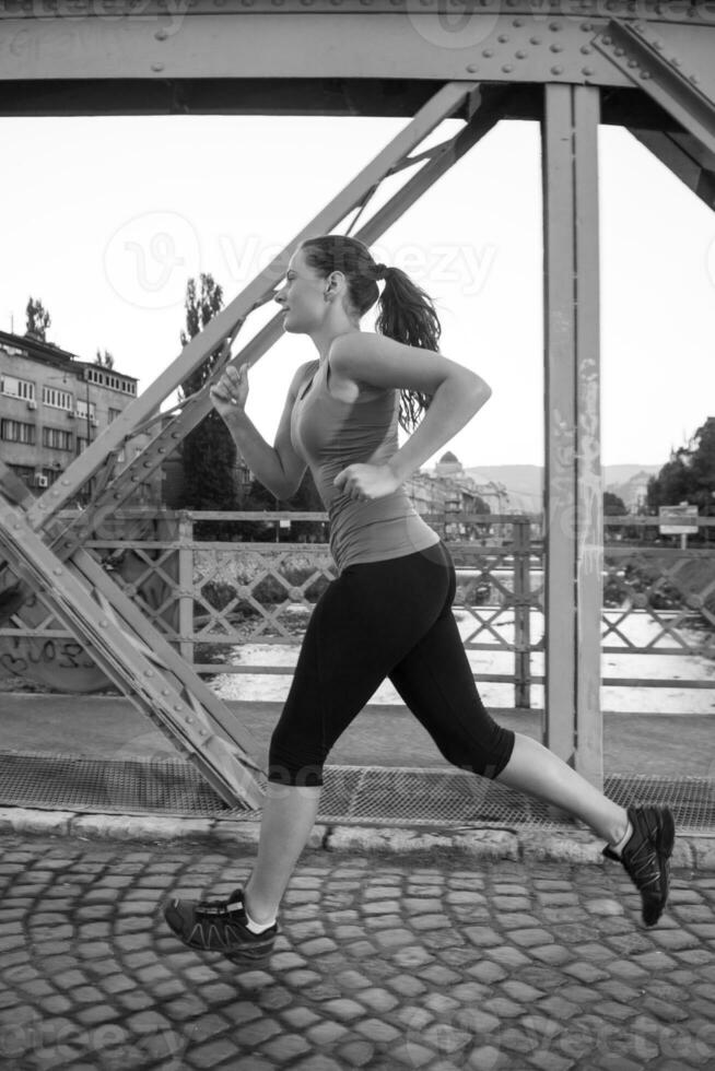 woman jogging across the bridge at sunny morning photo