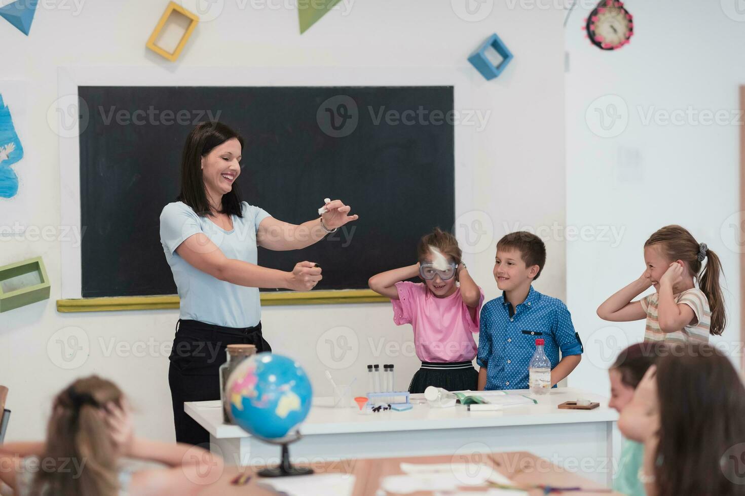 Elementary School Science Classroom Enthusiastic Teacher Explains Chemistry to Diverse Group of Children, Little Boy Mixes Chemicals in Beakers. Children Learn with Interest photo