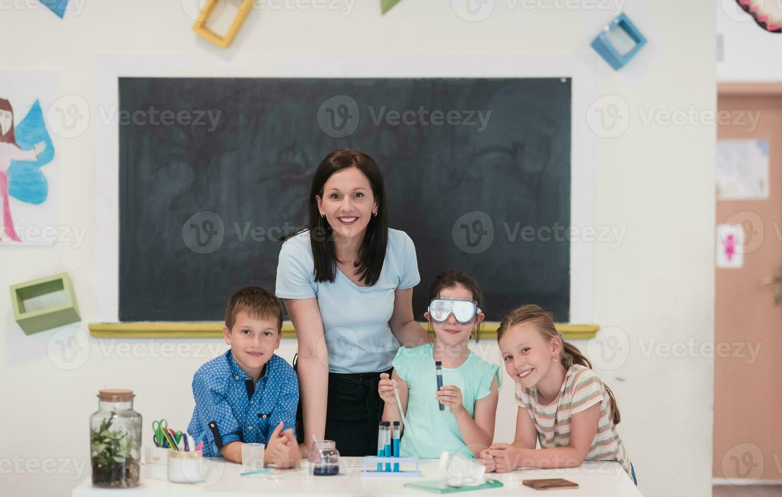 Elementary School Science Classroom Enthusiastic Teacher Explains Chemistry to Diverse Group of Children, Little Boy Mixes Chemicals in Beakers. Children Learn with Interest photo