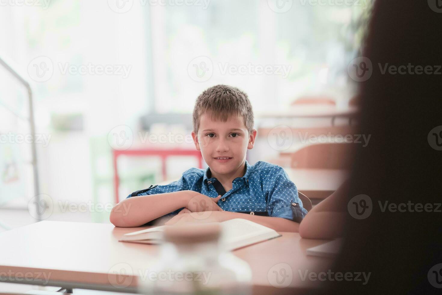 Little boy sitting in elementary school drawing on paper with their friends while sitting in a modern classroom photo