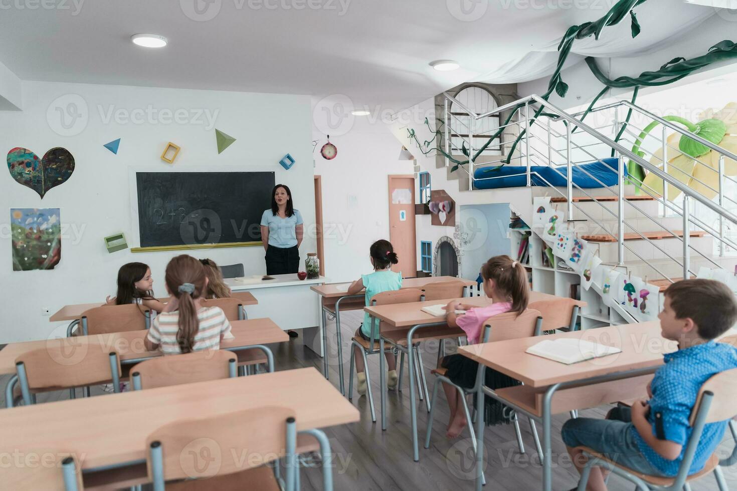 Elementary school. The female teacher helping the child student while writing the answer on the chalkboard. photo