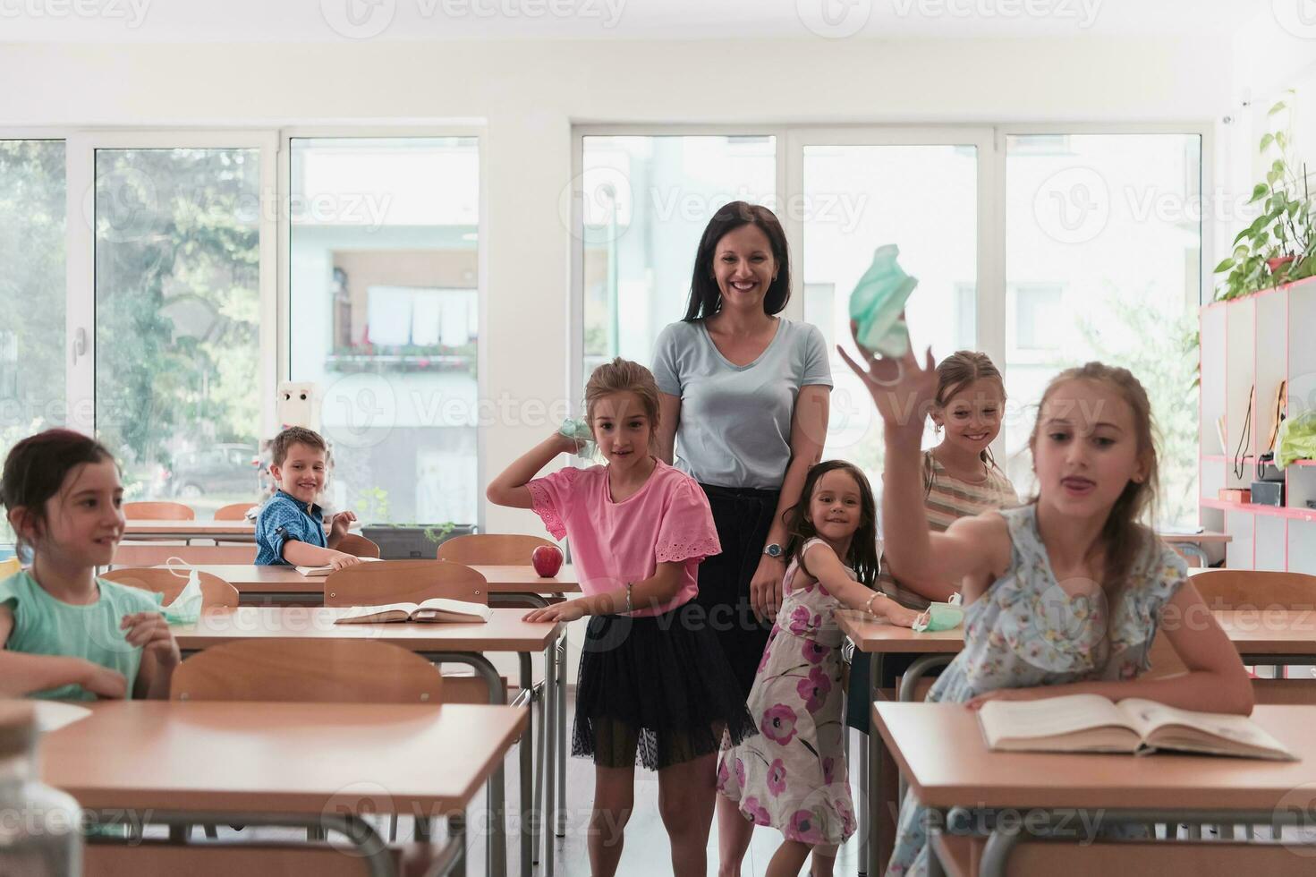 The end of the pandemic. The teacher in the school takes off the protective masks with the students photo