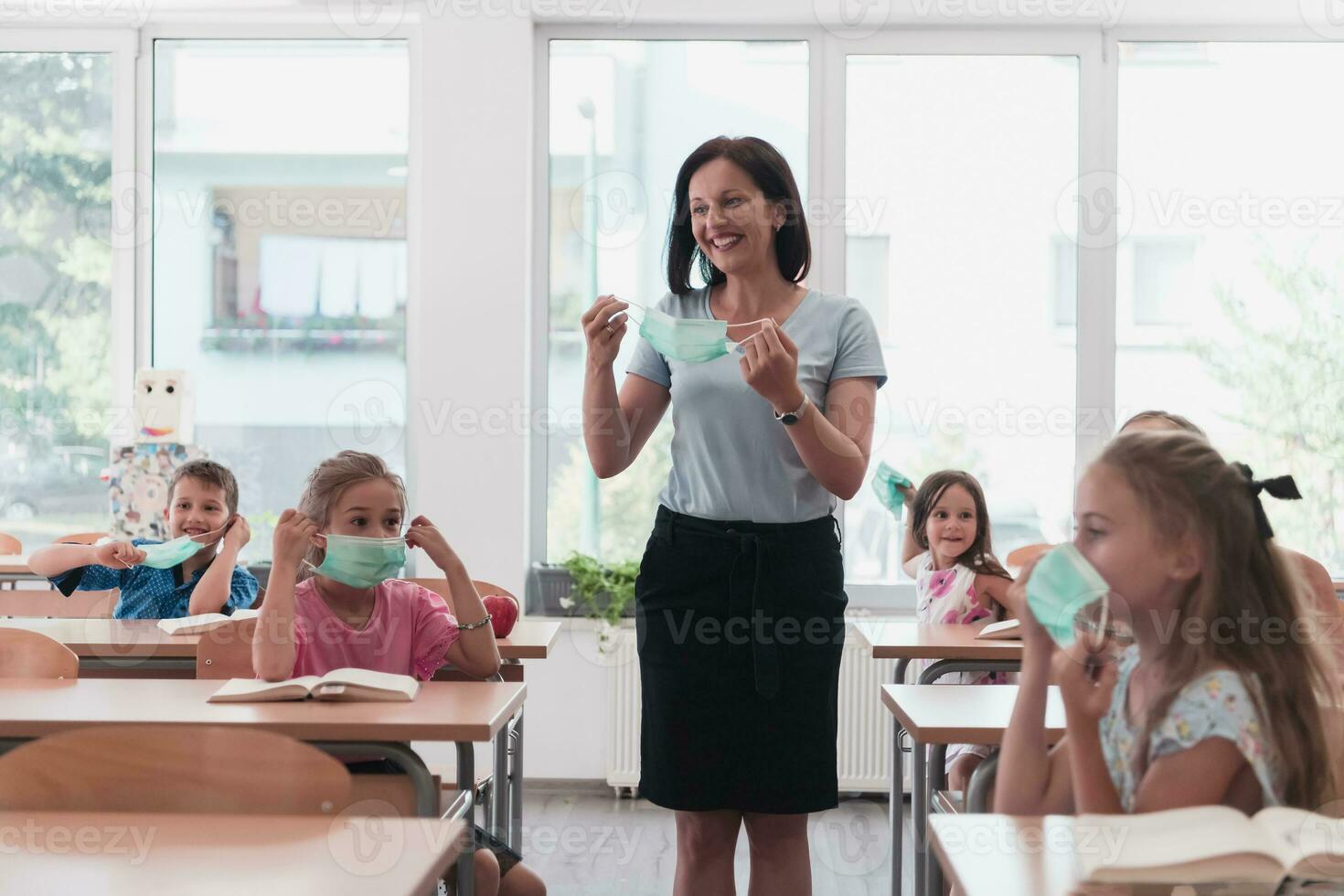 The end of the pandemic. The teacher in the school takes off the protective masks with the students photo