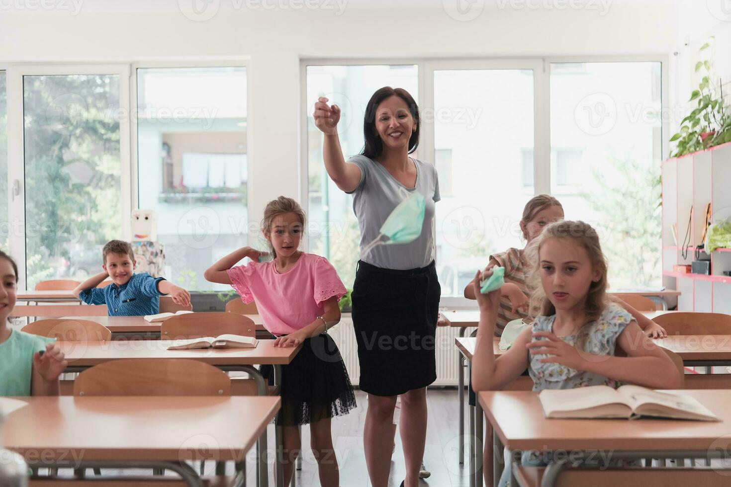 The end of the pandemic. The teacher in the school takes off the protective masks with the students photo