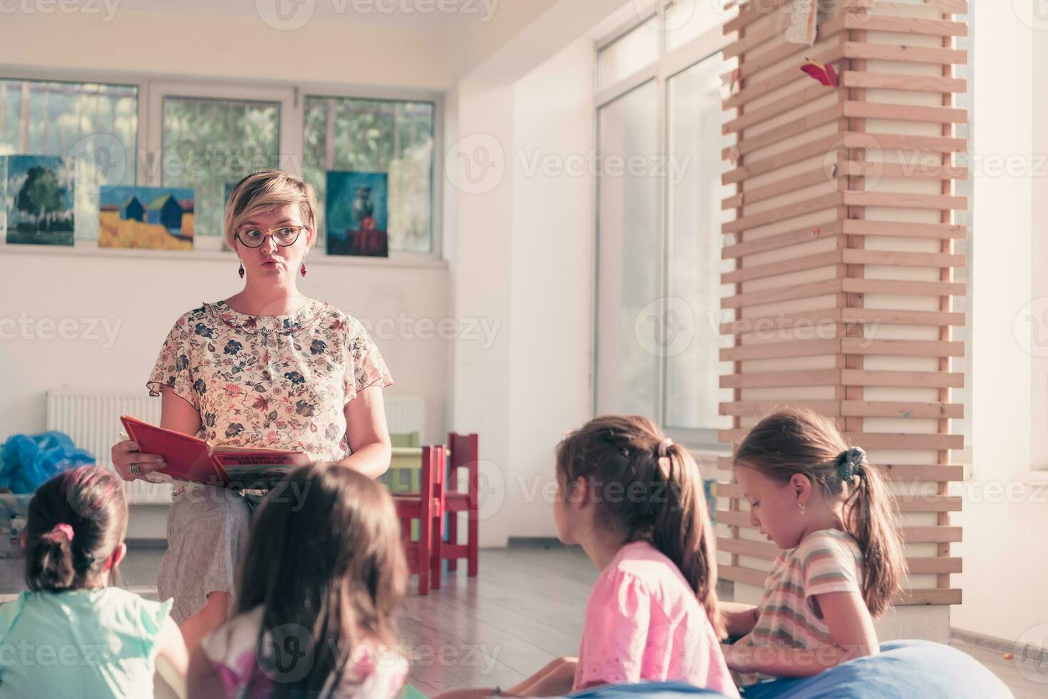 Reading time in elementary school or kindergarten, teacher reading a book to kids in elementary school or kindergaden. Selective focus photo