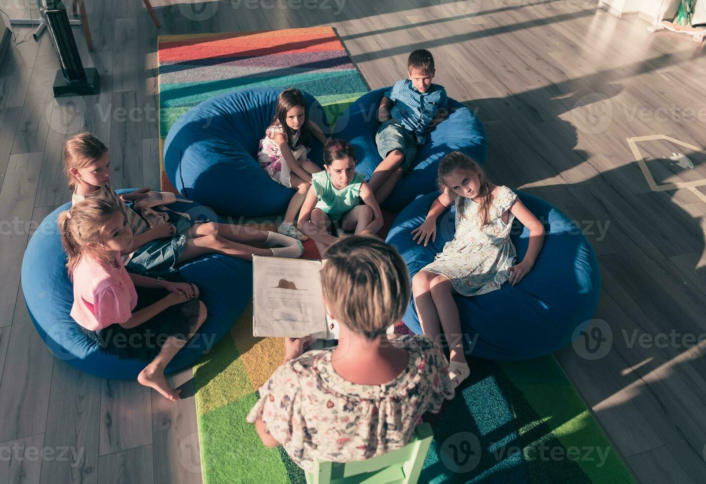 Reading time in elementary school or kindergarten, teacher reading a book to kids in elementary school or kindergaden. Selective focus photo