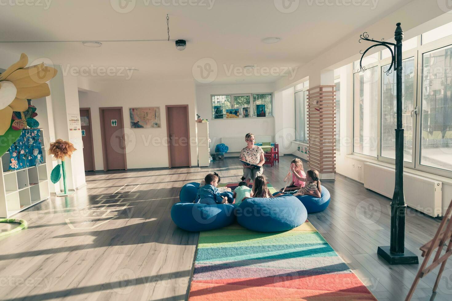 Reading time in elementary school or kindergarten, teacher reading a book to kids in elementary school or kindergaden. Selective focus photo