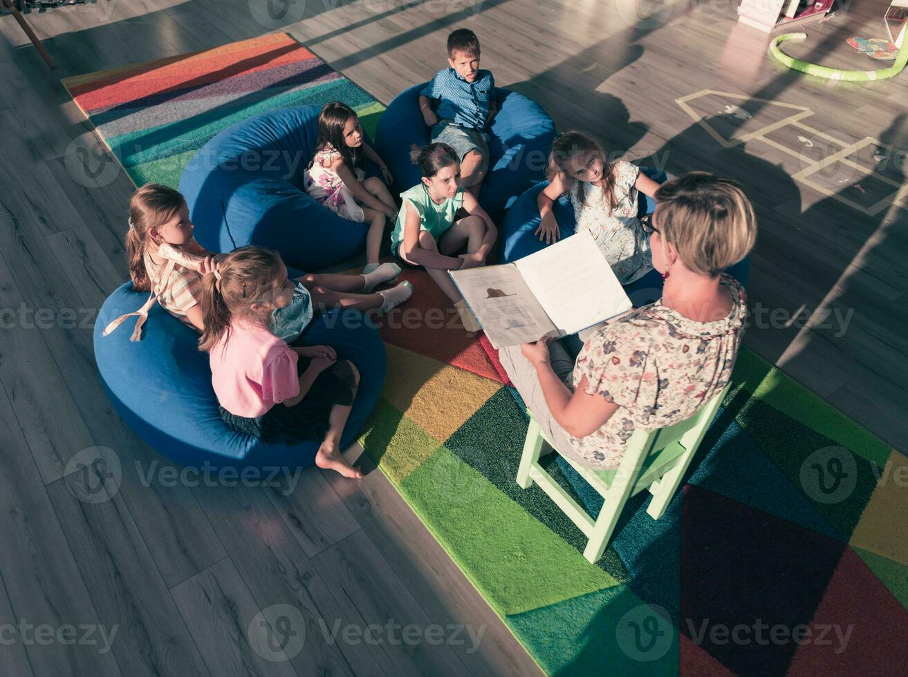 Reading time in elementary school or kindergarten, teacher reading a book to kids in elementary school or kindergaden. Selective focus photo