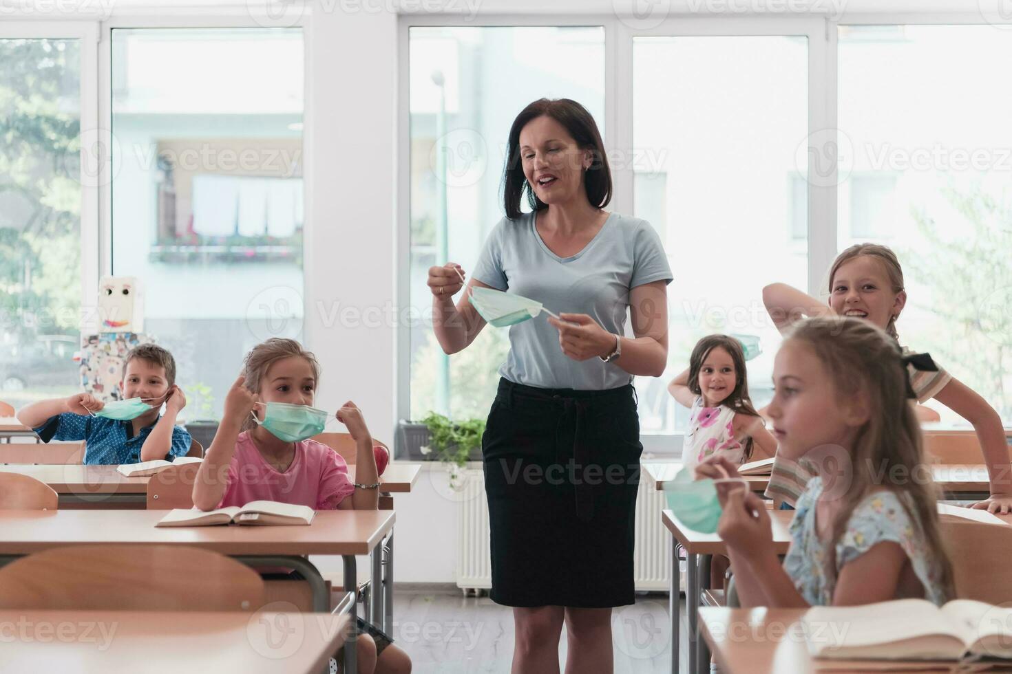 The end of the pandemic. The teacher in the school takes off the protective masks with the students photo