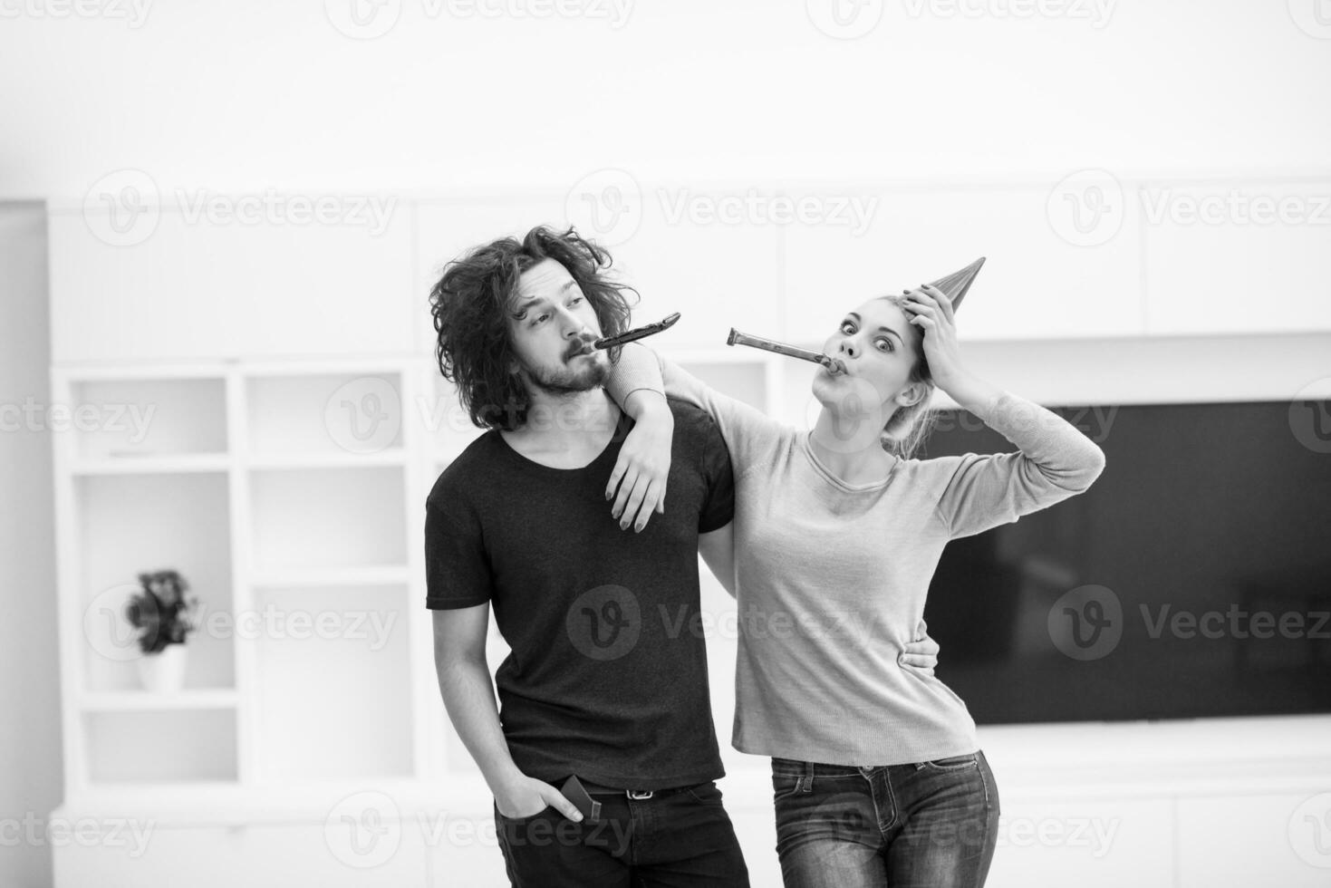 couple in party hats blowing in whistle photo