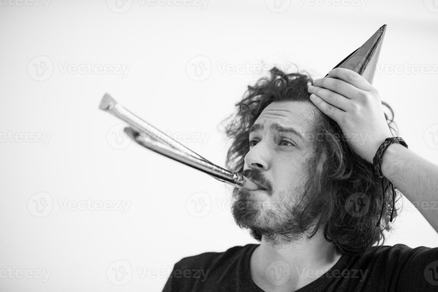 Portrait of a man in party hat blowing in whistle photo