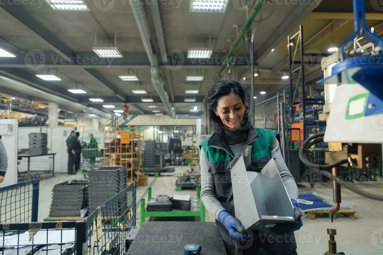 a woman working in a modern metal factory assembles parts for a new machine photo