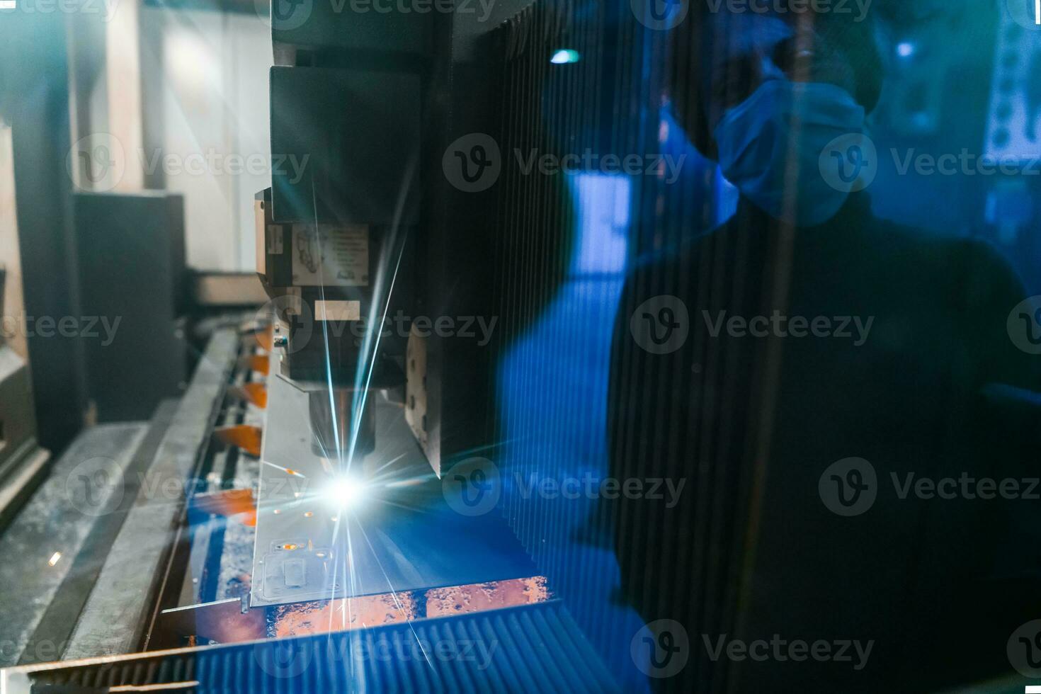Sparks fly out machine head for metal processing laser metal on metallurgical plant background. Manufacturing finished parts for automotive production concept photo