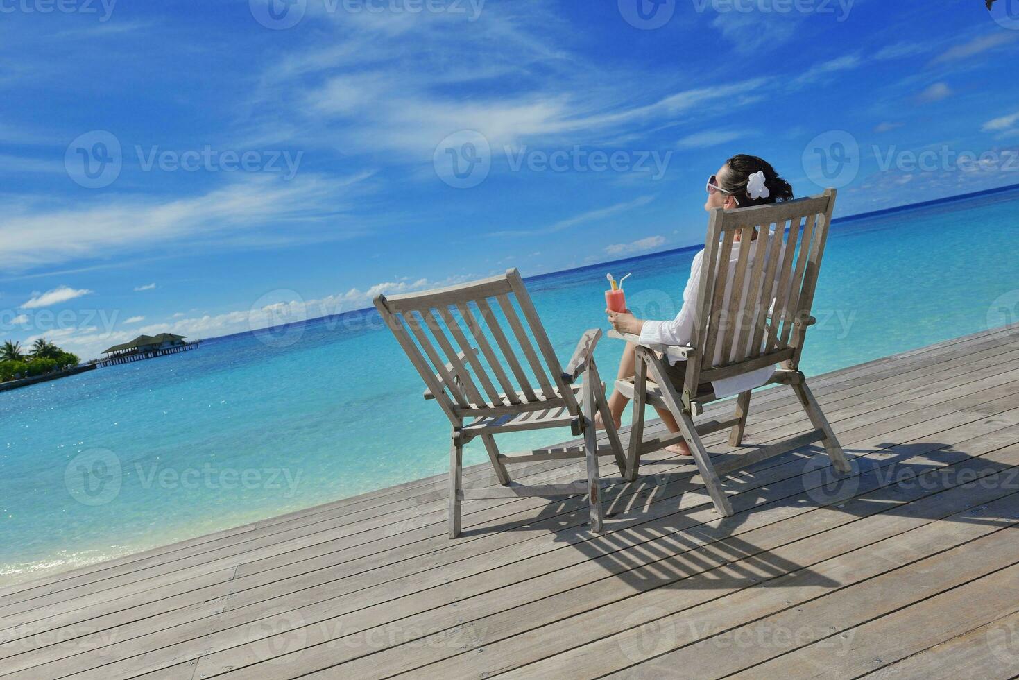 Beautiful young woman with a drink by the sea photo