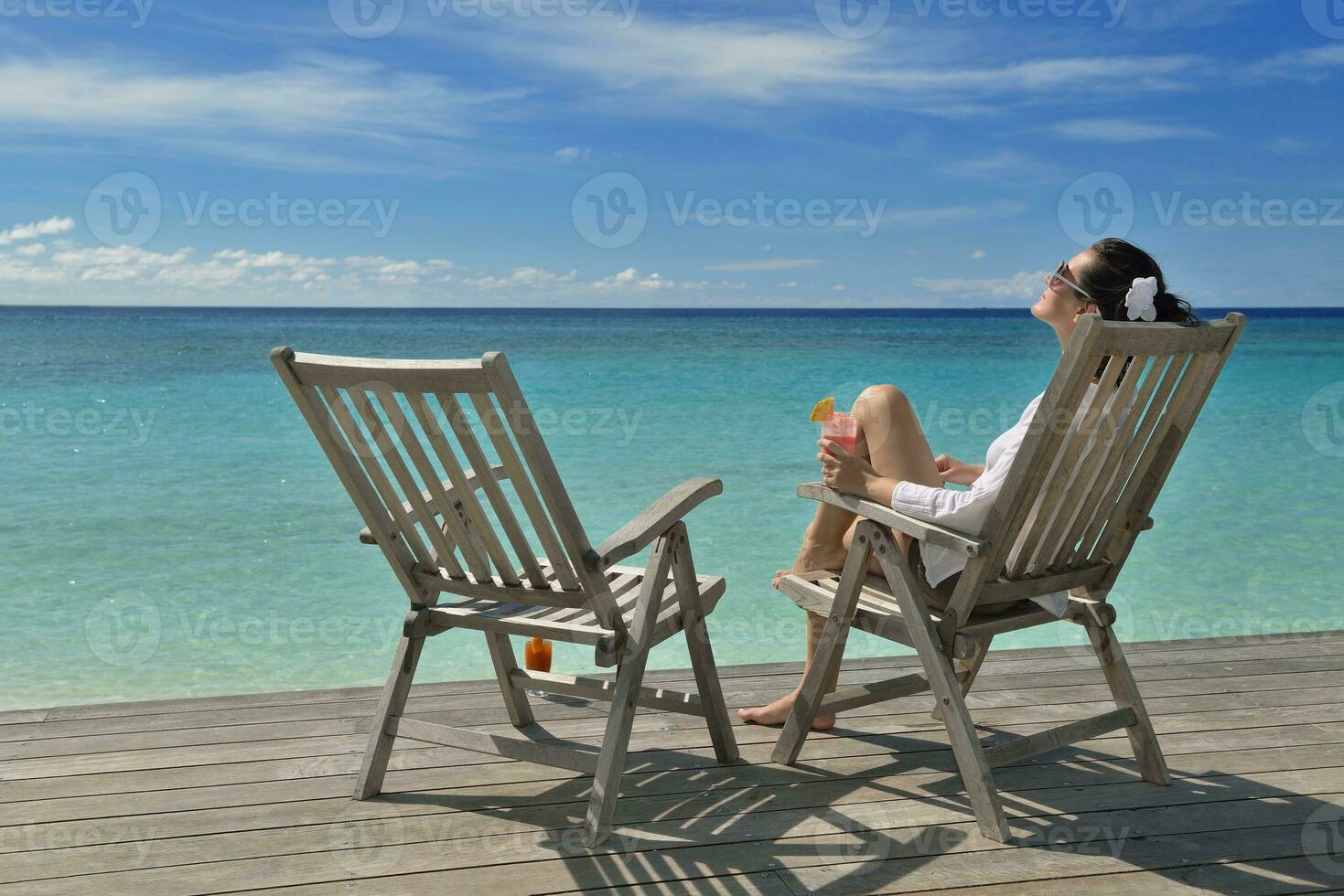 Beautiful young woman with a drink by the sea photo